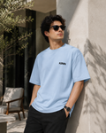 Men wearing KØMN sky blue oversized crewneck t-shirt with black logo front view, relaxed fit cotton tee