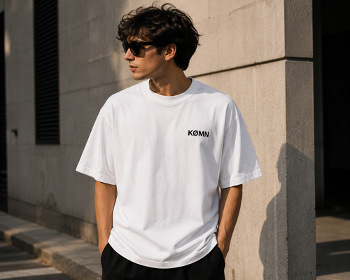 Men wearing KØMN white oversized crewneck t-shirt front view with black logo, heavyweight cotton oversized fit