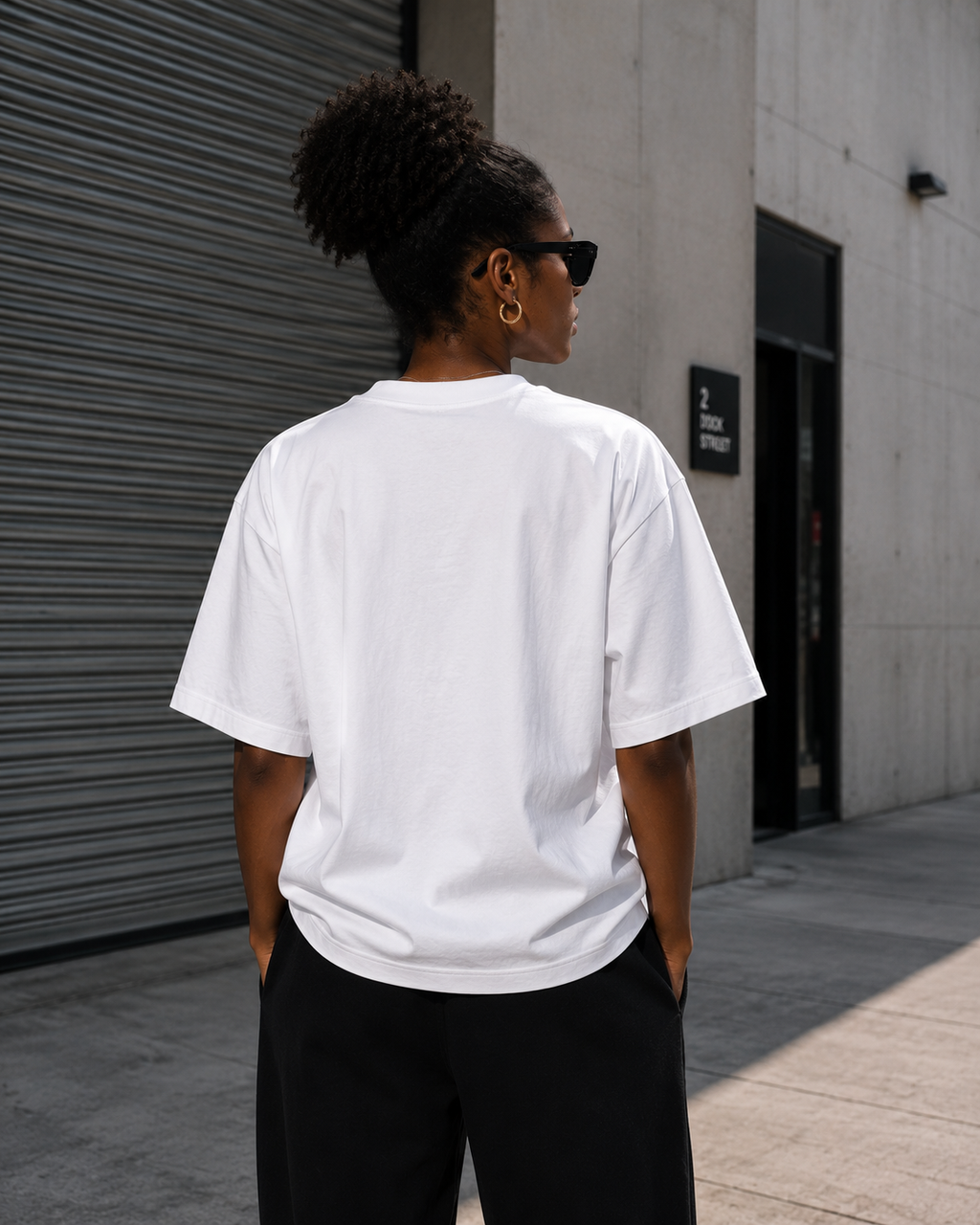 Back view of woman wearing KØMN white oversized crewneck t-shirt, minimal heavyweight cotton everyday tee