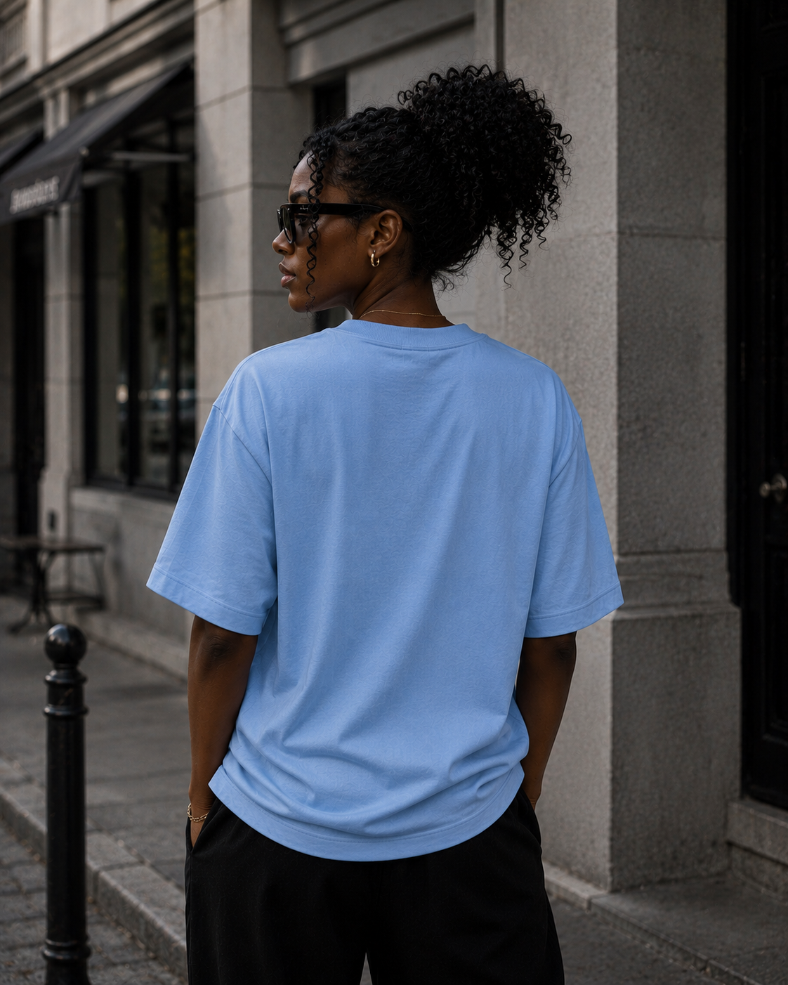 Woman wearing KØMN light blue oversized t-shirt back view, relaxed cotton tee for everyday wear
