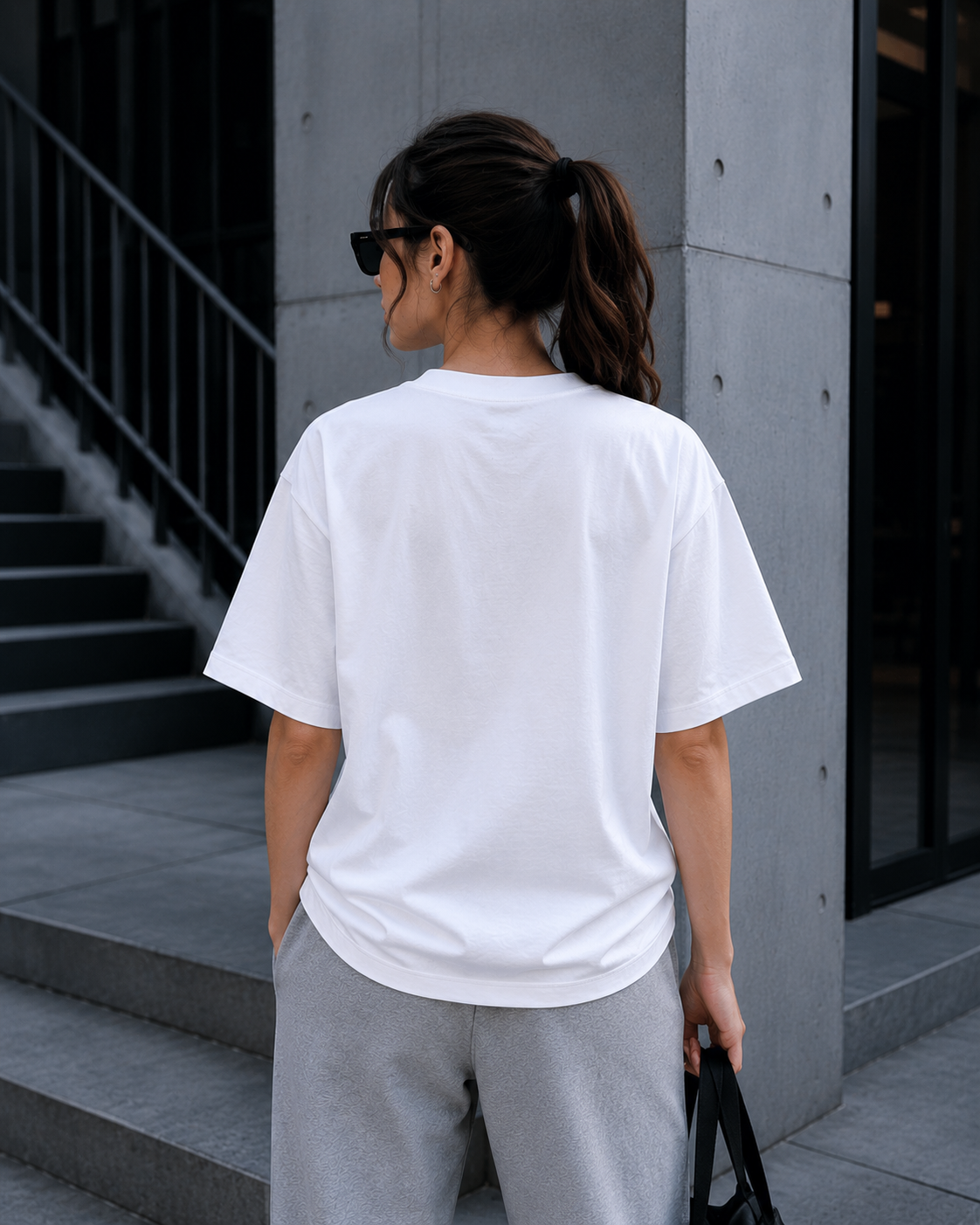 Back view of woman wearing KØMN white oversized t-shirt in relaxed fit, 100% cotton heavyweight tee