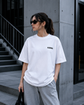 Woman wearing KØMN white oversized t-shirt front view with black chest logo, relaxed fit cotton tee