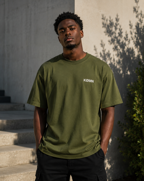 Man wearing KØMN olive green oversized t-shirt front view with chest logo, 100% cotton everyday tee